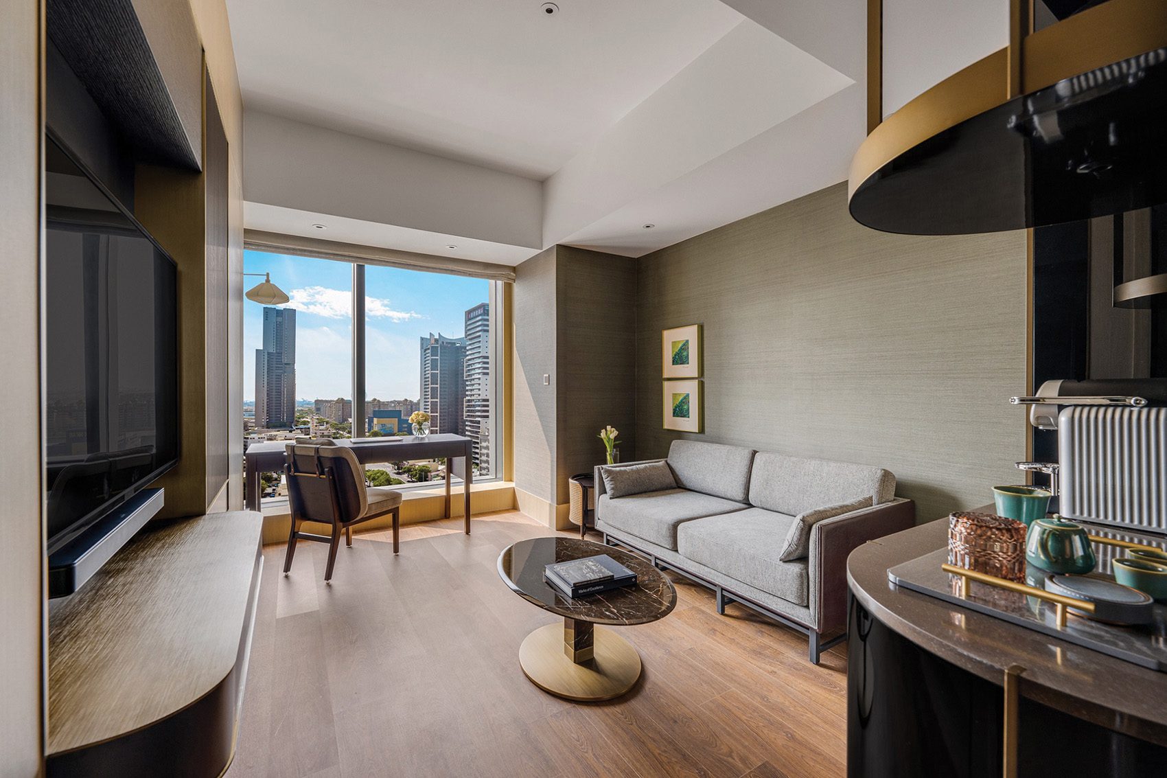 A room with a couch, coffee table, TV, desk and chair in the InterContinental Kaohsiung. 