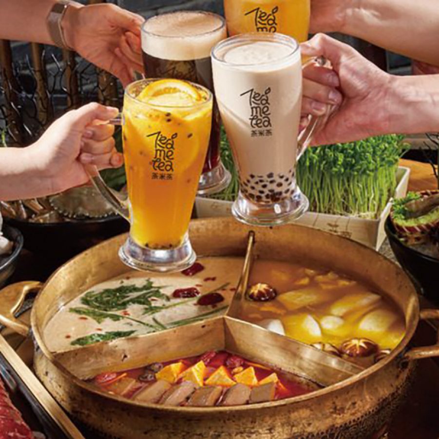 Four outreached arms clinking fruit tea and bubble tea glasses over a table full of hot pot ingredients at Coucou Hot Pot‧Tea Break.