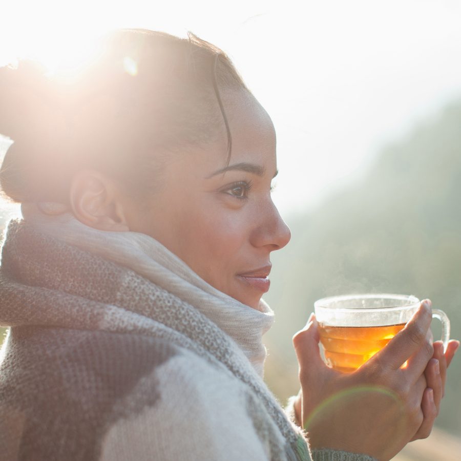 A woman wearing a scarf holding a cup of tea.