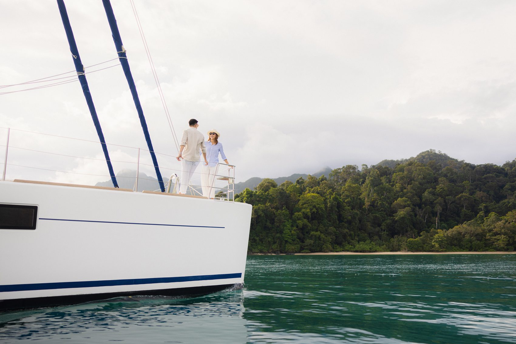 A man and woman standing aboard The Datai Langkawi’s catamaran.   