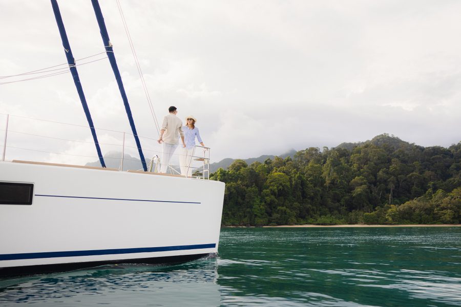 A man and woman standing aboard The Datai Langkawi’s catamaran.   
