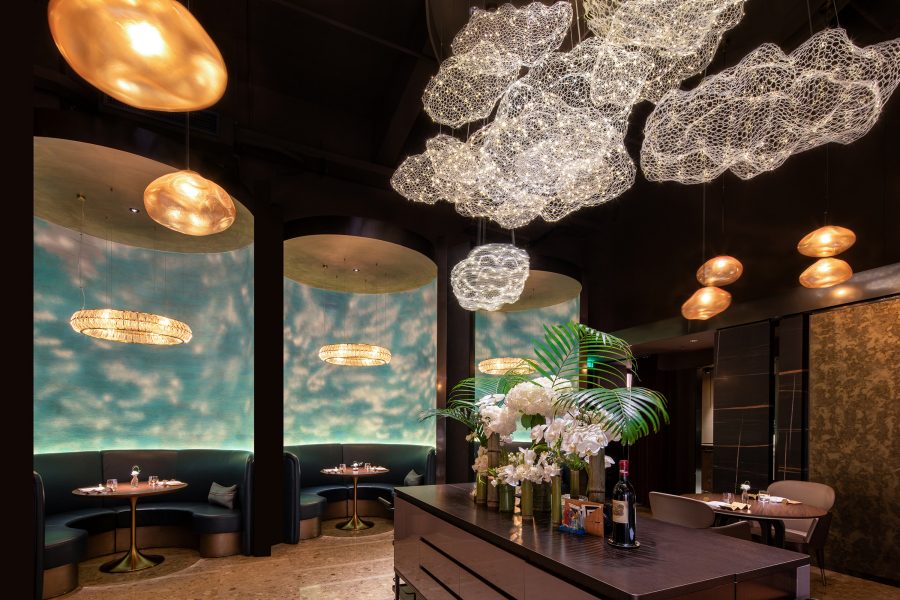 The interior of Avant, which includes cloud-shaped ceiling lights, private booths with sky-blue walls, and a bar table. 