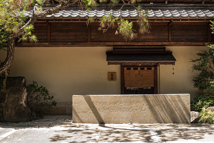 The façade of Shokutei Nihonryori, with traditional Japanese wooden architecture and trees. 