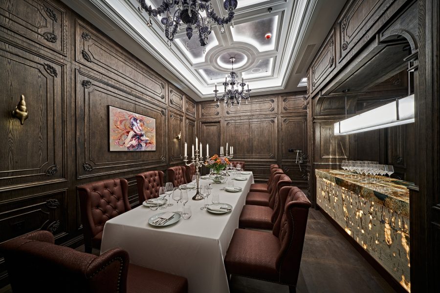 A room with a long dining table, candelabra, dark wood walls and chandeliers at Stone Sal.