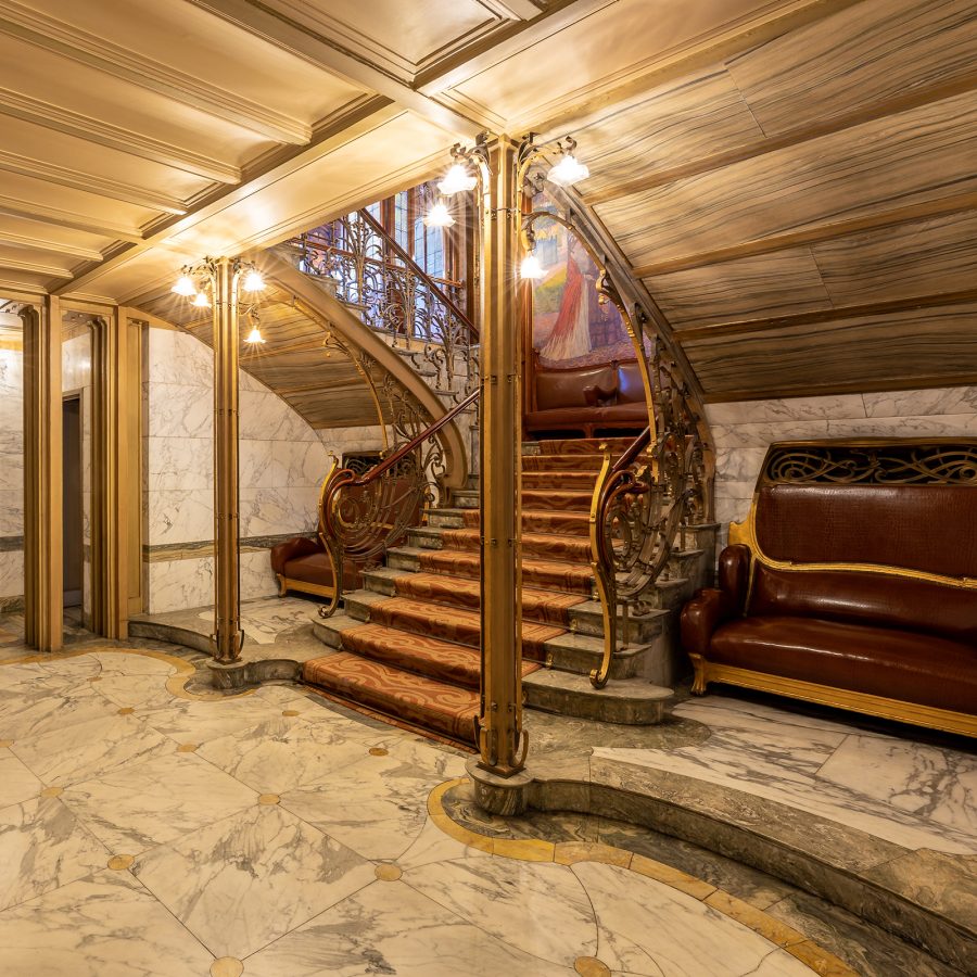 At the Art Nouveau Hotel Solvay, a staircase leads to a bar and lounge with a marble floor and curved ceiling.
