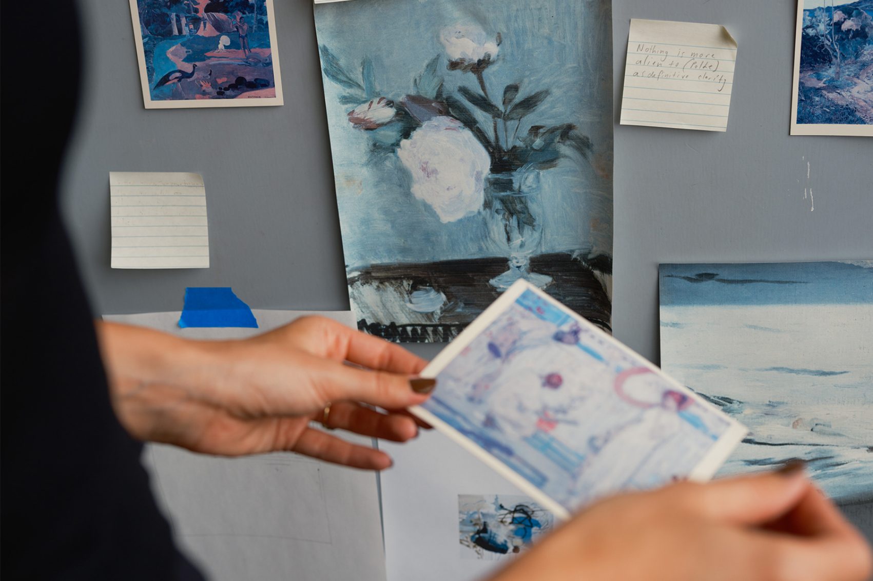 Close-up of a person pinning a photograph to a noticeboard 