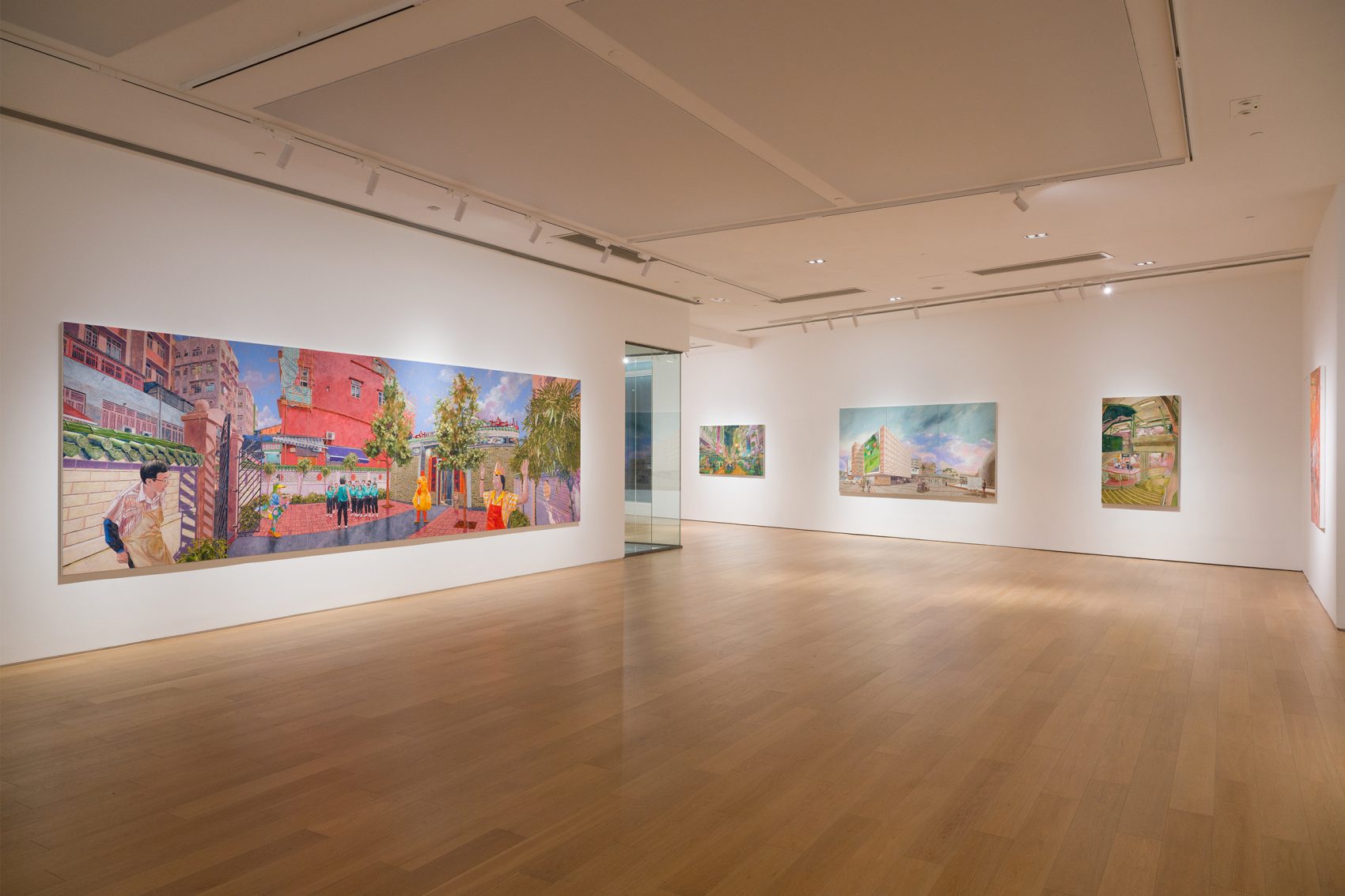 Large, colourful canvasas are displayed the walls of a spacious, softly lit gallery with wooden floors. 