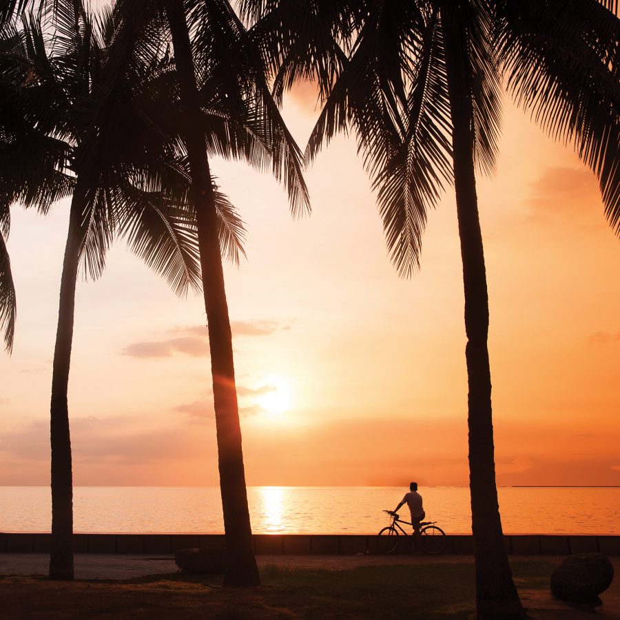 A man on a bike at Manila Bay at sunset.