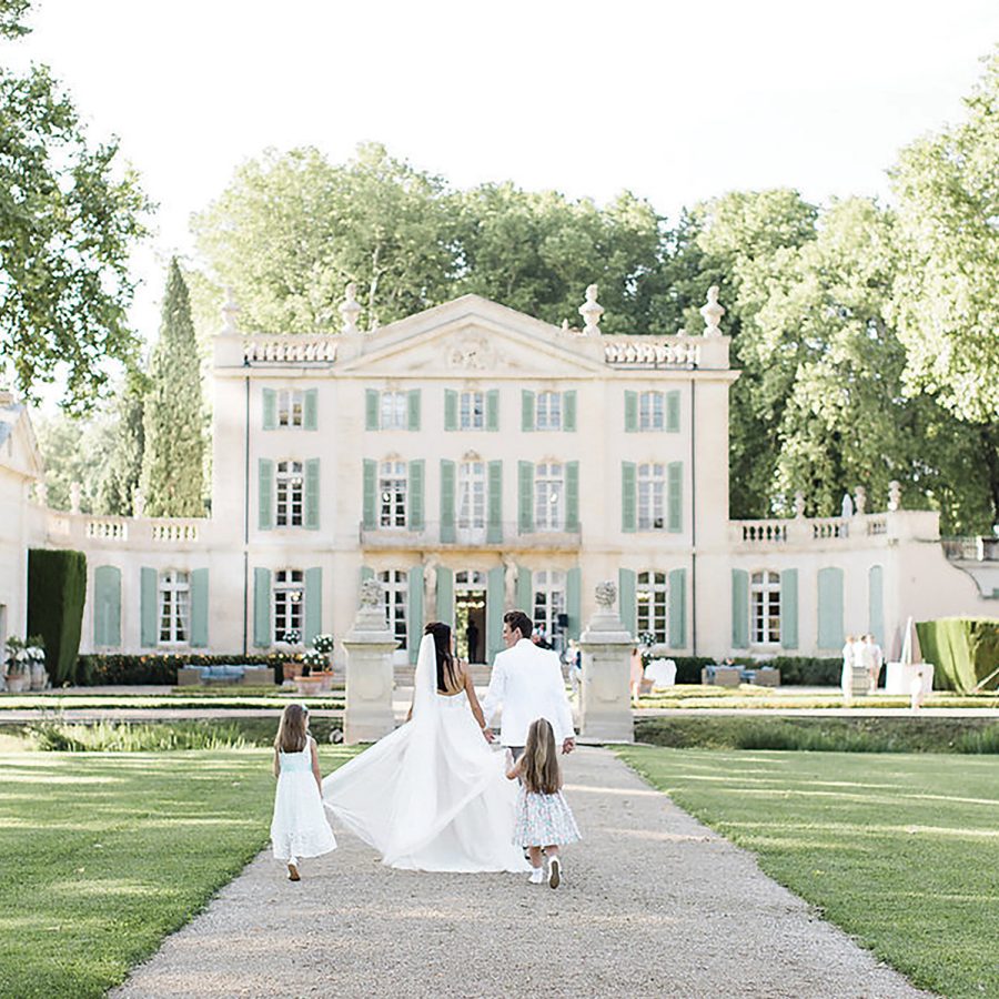 Shot of married couple and children walking towards Chateau de Torreau France