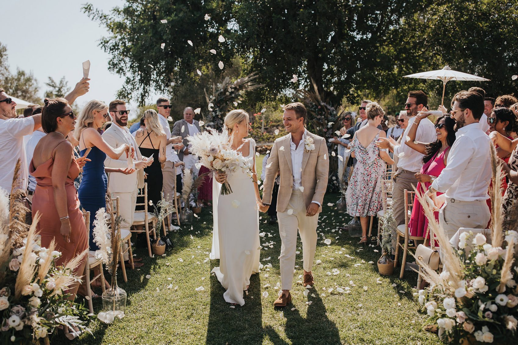 Couple walking down the aisle as people throw flowers