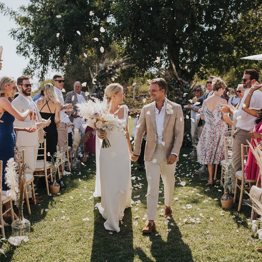Couple walking down the aisle as people throw flowers