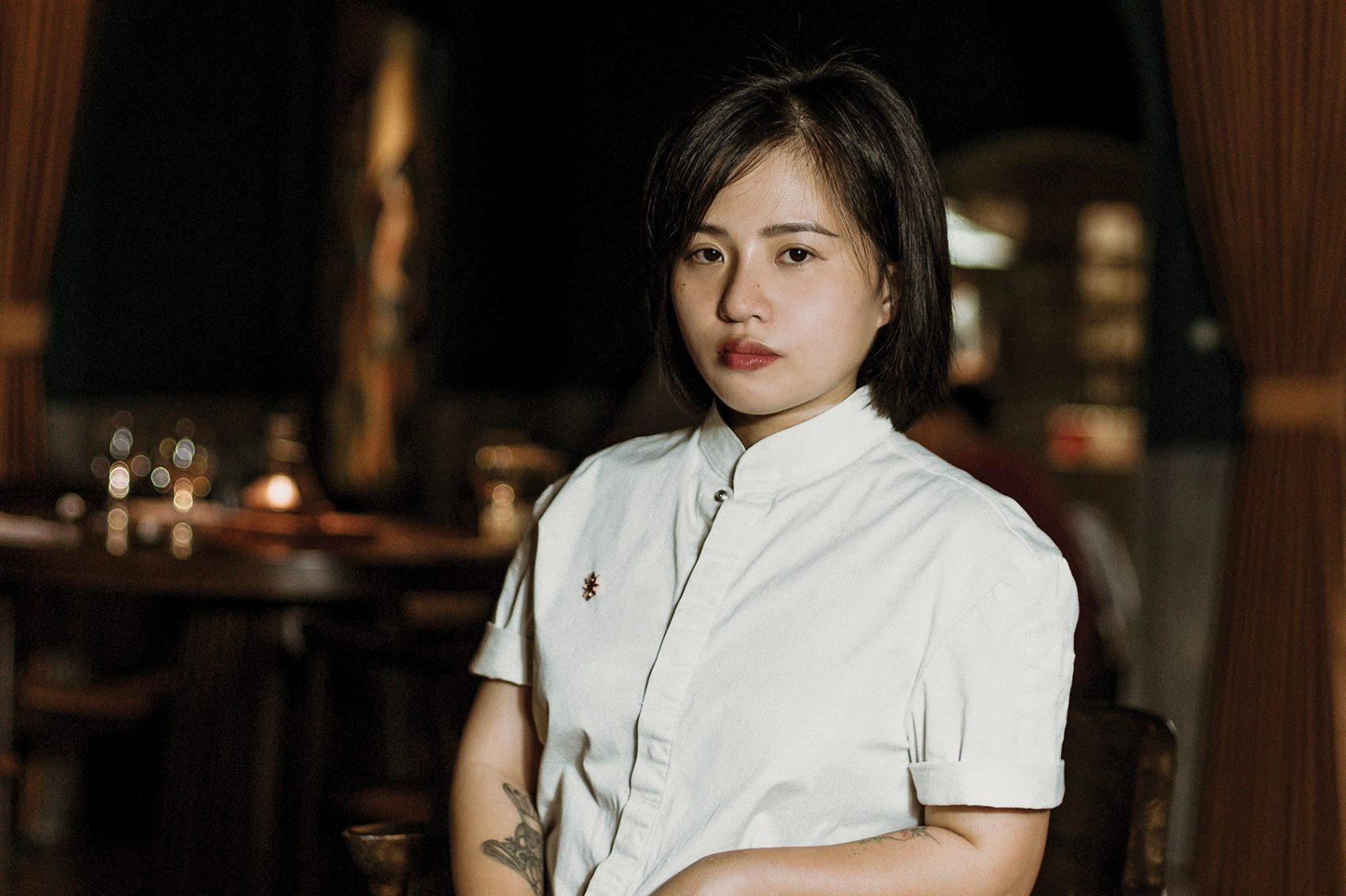 Head chef of Gia, Sam Tran, poses for a picture against a blurred background.