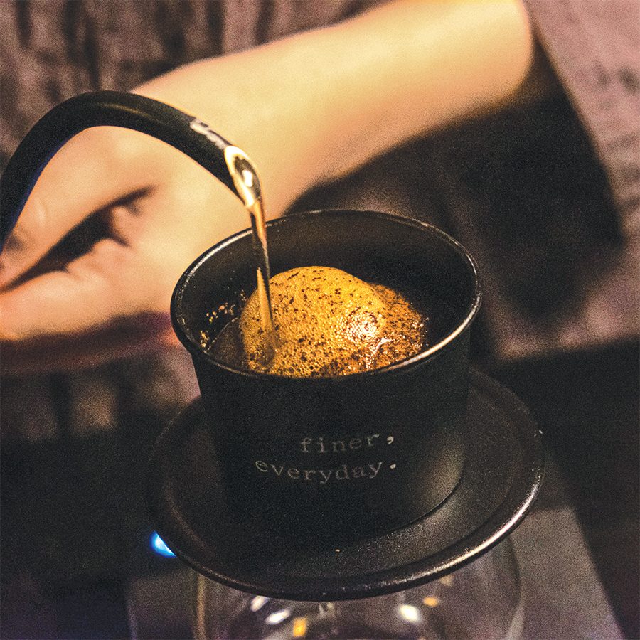 Water pours out of a kettle over a coffee filter at Phin Bar by Refined. 