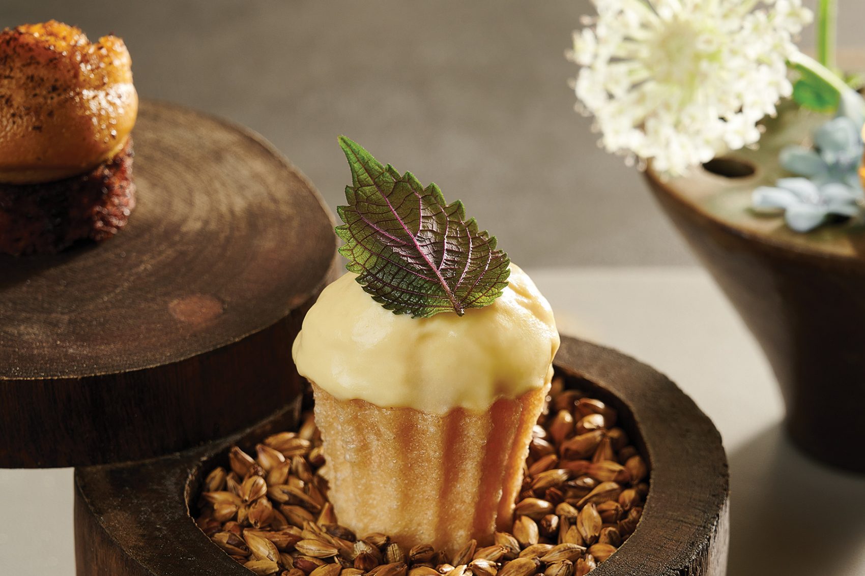 A cupcake topped with icing and a leaf, sits on a decorative dish at Studios, Hanoi.