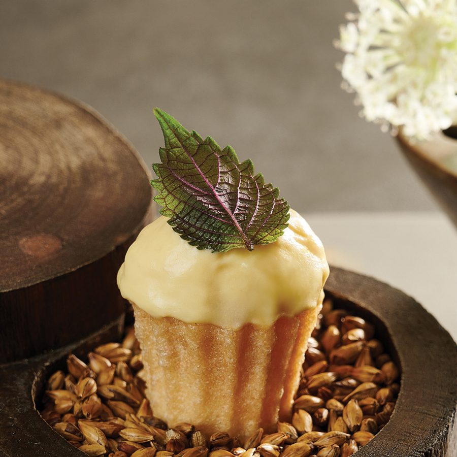 A cupcake topped with icing and a leaf, sits on a decorative dish at Studios, Hanoi.
