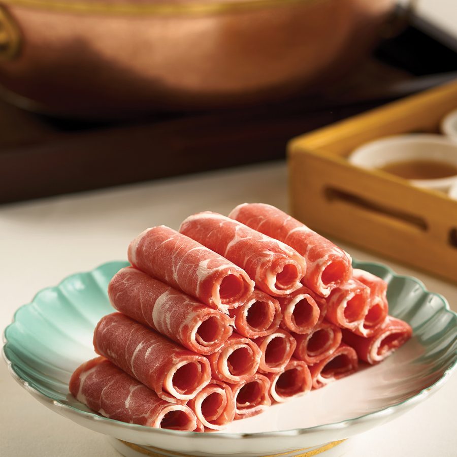 A closeup of a green plate stacked with frozen and rolled wagyu beef slices served at Dong Lai Shun restaurant in Hong Kong