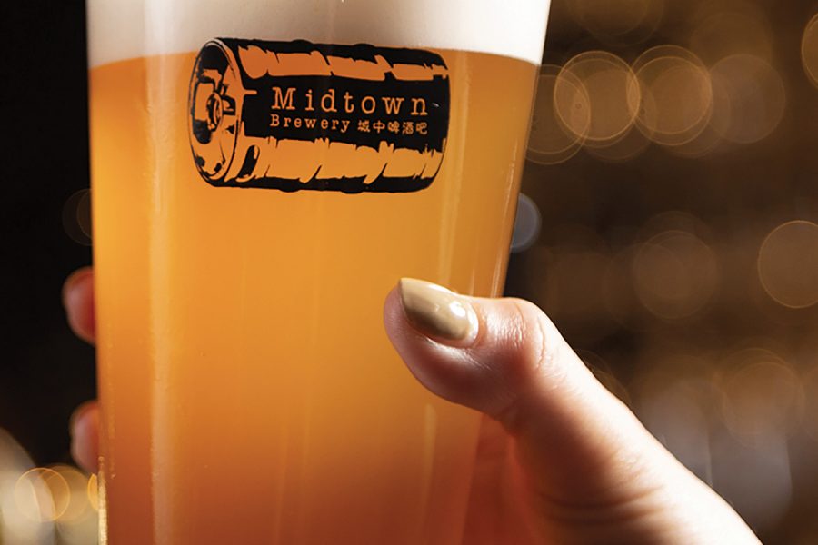 A hand holding a glass of beer from Midtown Brewery.