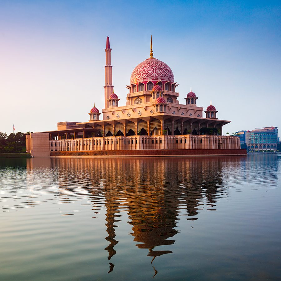 A landscape view of Putrajaua’s pink mosque Masjid Putra and the man-made lake at Putra Square at sunset.