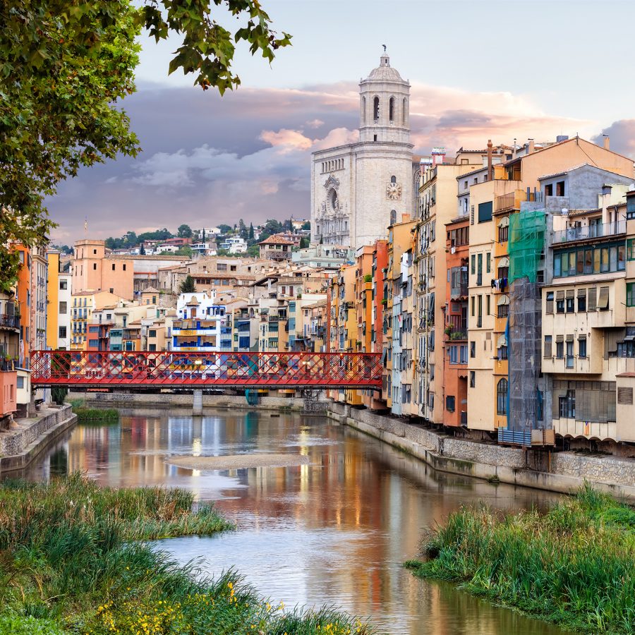 Girona Cathedral and other colourful buildings next to Eiffel Bridge, which sits over Onyar River. 