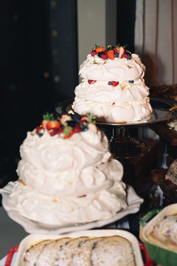Two three-tiered pavlovas topped with strawberries are displayed on cake stands at The Rescued Feast 3.0.
