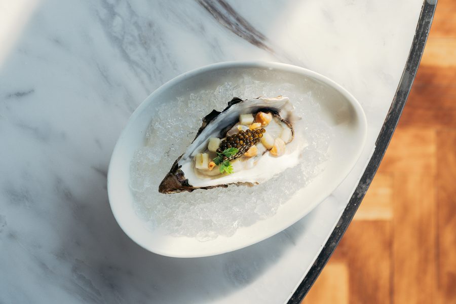 Oyster with toppings served on a bed of ice