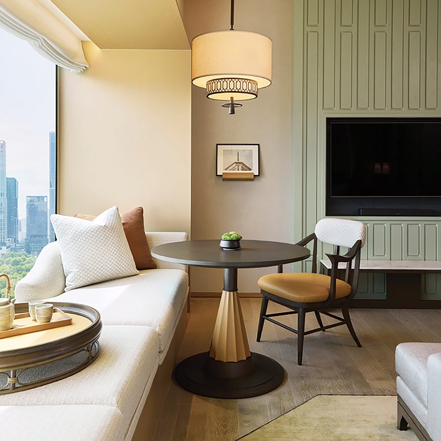 A view of the interiors of a guestroom at Dusit Thani Bangkok, featuring an elegant design, coffee table and plush reading nook by the window