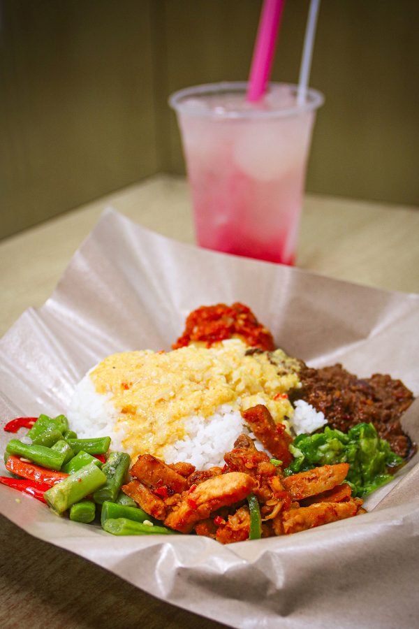 A closeup of a plate of nasi campur with beed rendang and side dishes with a glass of es kolang kaling with palm seed and red syrup served at Warung Malang in Causeway Bay.
