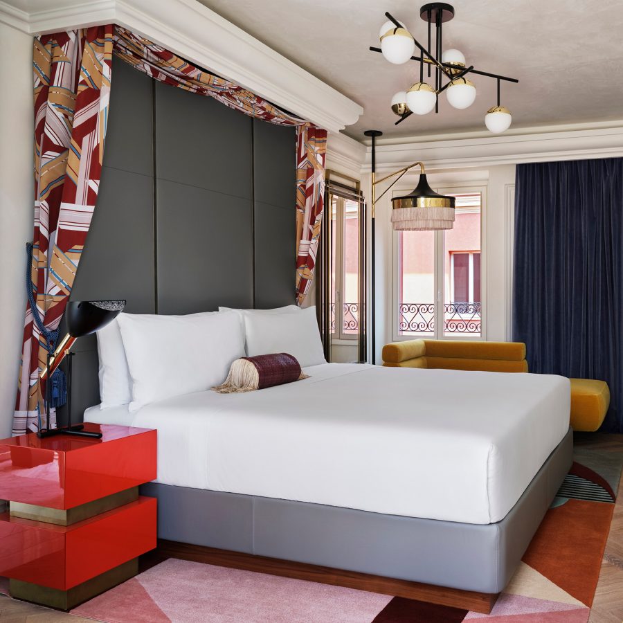 An interior view of a bedroom at W Hotel Rome with geometric designs on the rug and drapes.
