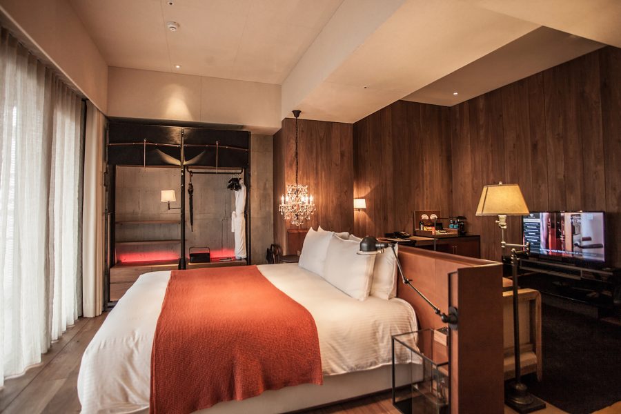 View of a dark wood hotel room with a large bed at the Hotel Proverbs.