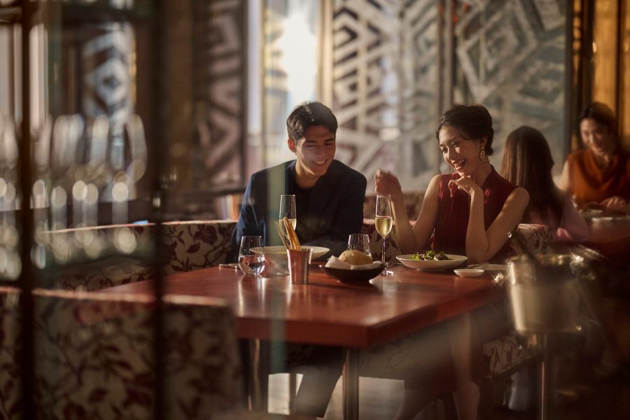 A man and a woman eating and smiling as they eat at the Mandarin Oriental Taipei.