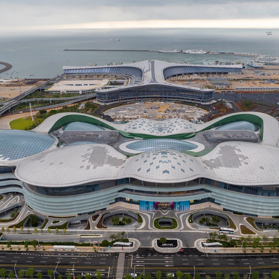 CDF Haikou International Duty Free City seen from the outside and above is a massive complex, its outline shaped by a series of interconnected convex curves. 