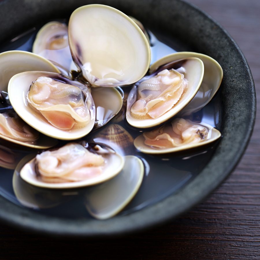 A bowl of clams steamed with salt and sake, available at Kuroudo Kuriya Kinshachi, is placed on a table. 