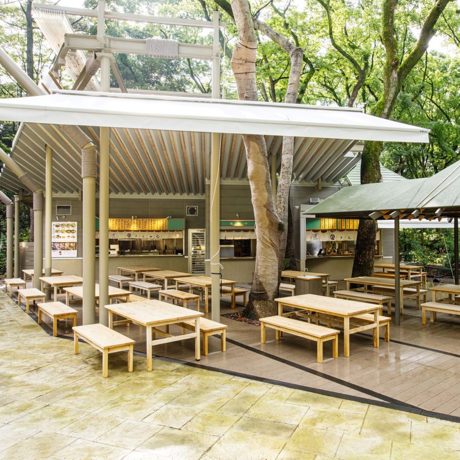 Exterior of the Jingu branch of Miya Kishimen, which offers dining tables next to a lush forest.