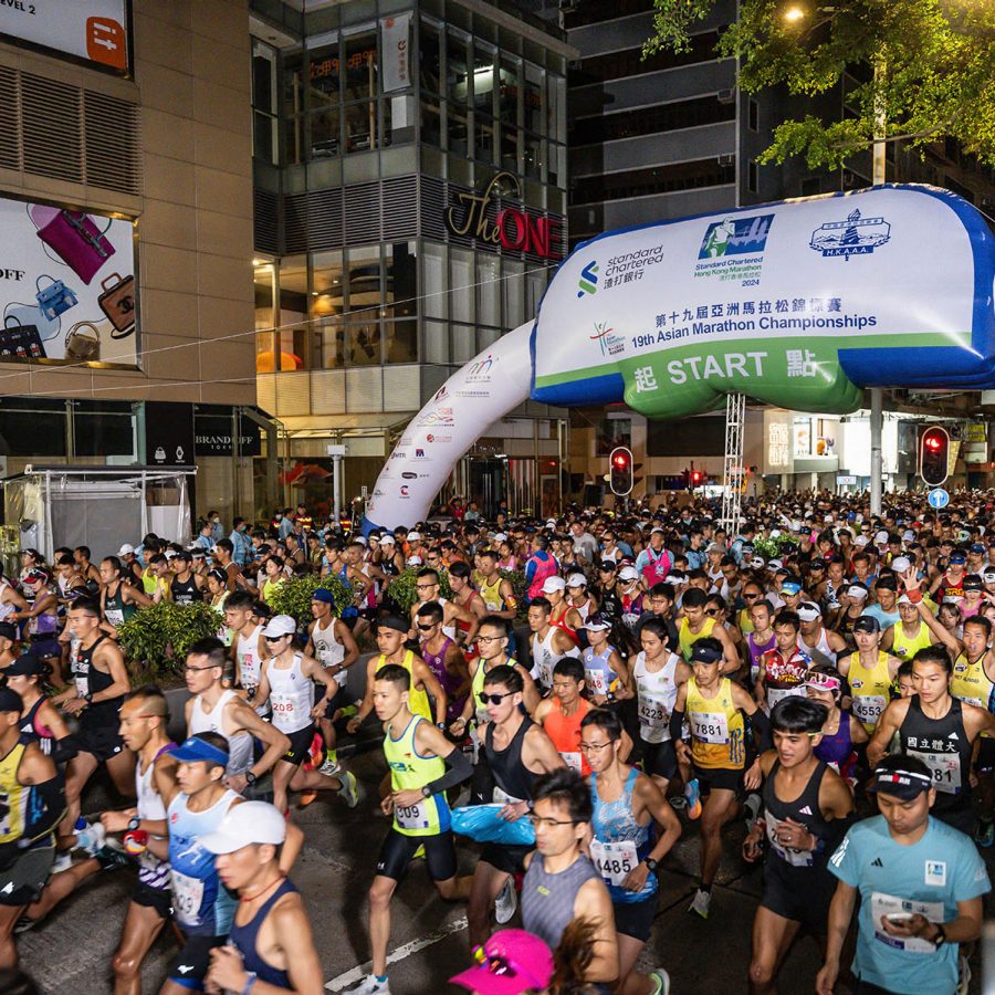 Crowds of runners passing under an arch at the Standard Chartered Hong Kong Marathon.