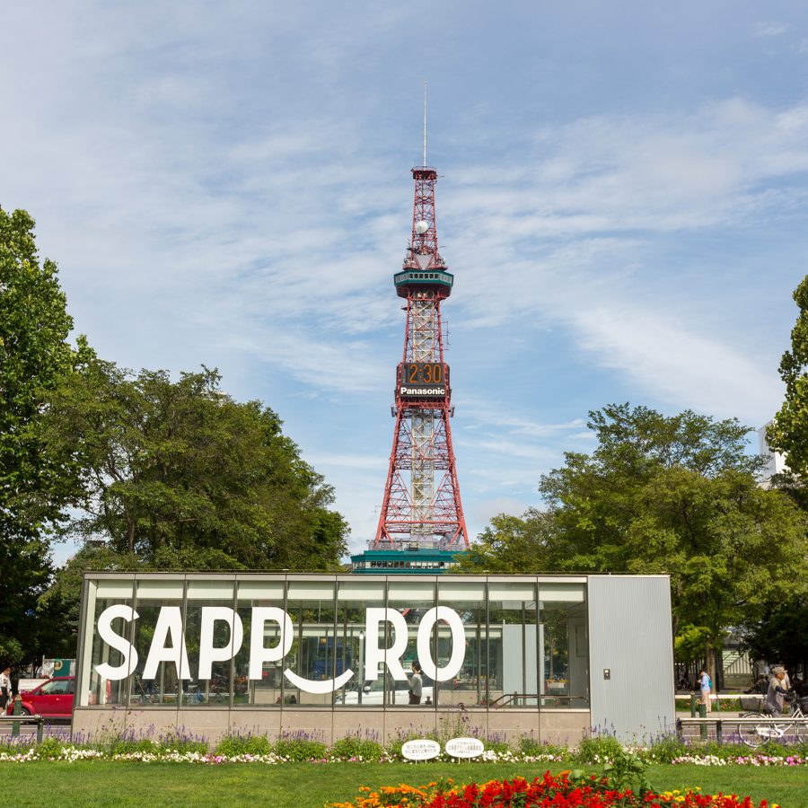 The exterior of a subway station entrance in Odori Park reads “Sapporo” as the Sapporo TV Tower stands tall in the distance.