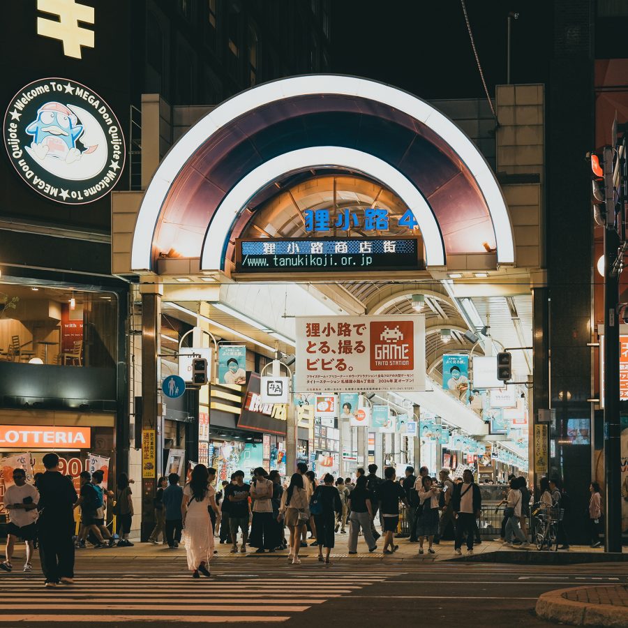 Tanukikoji Shopping Street in Sapporo bustles with pedestrians at night while a Don Quijote signboard stands next to it. 
