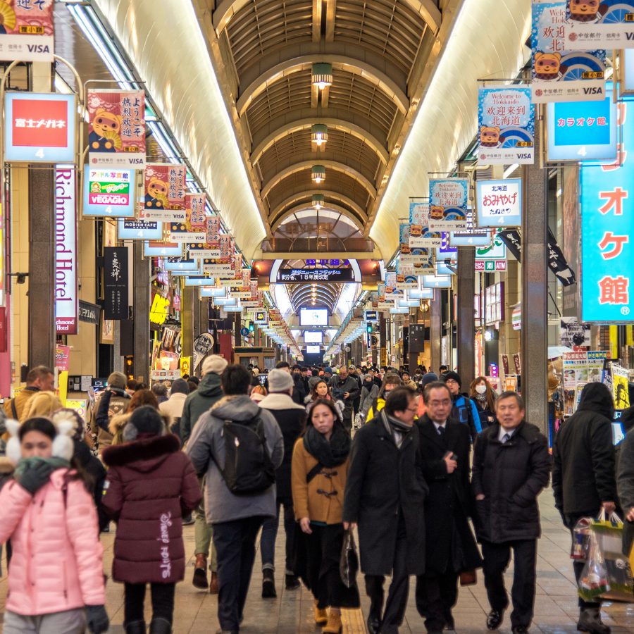 People bundled up in winter clothing walk through Tanukikoji Shopping Street in Sapporo. 