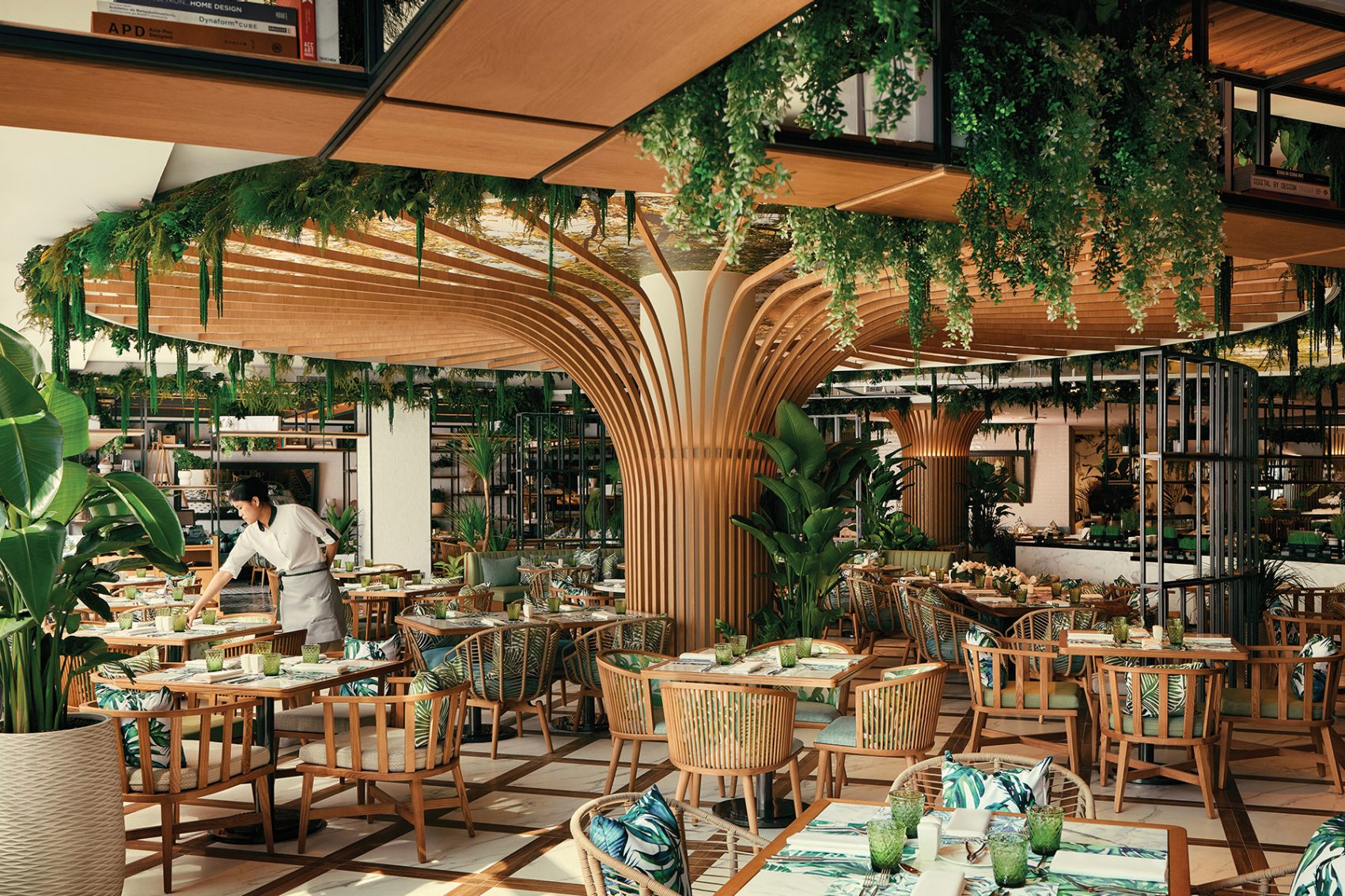 At nature-inspired restaurant Embu, a large tree-shaped column covered in hanging foliage stands in the centre of the room, surrounded by wooden tables and chairs. Plants and foliage are placed throughout the restaurant.