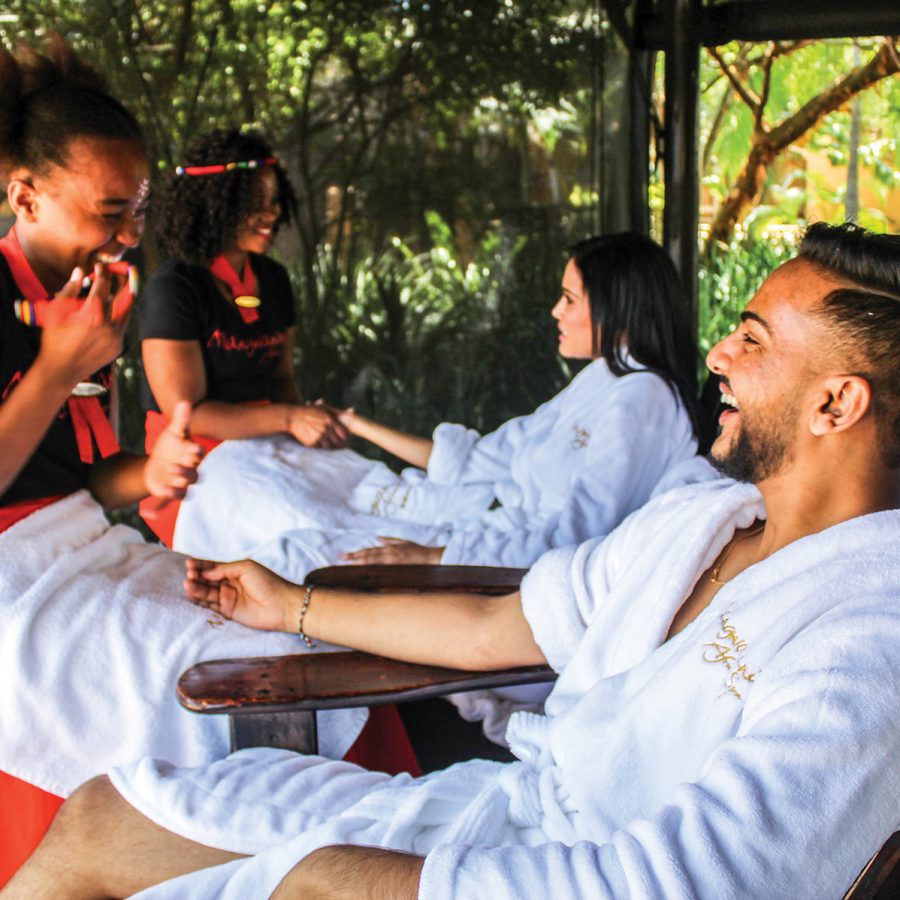 A couple and their masseuses smile at each other during a treatment at the Mangwanani African Spa, which is open to the elements.