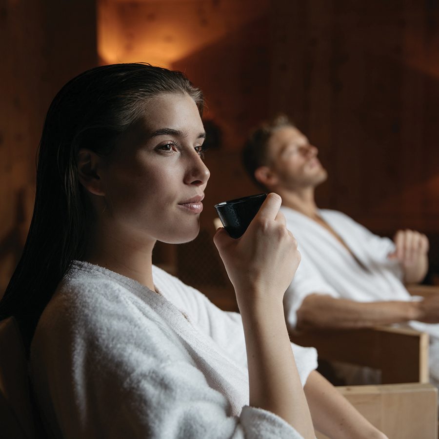 A woman sips from a cup as she relaxes in a chair next to a man at the Mineralbad & Spa Samedan, which offers a couples’ package.