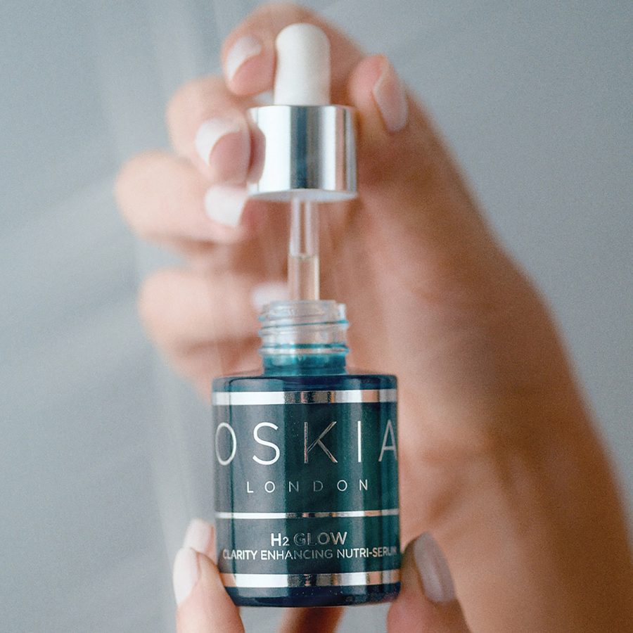 A closeup of a woman holding a dropper from a bottle of Oskia deep sleep treatment body oil