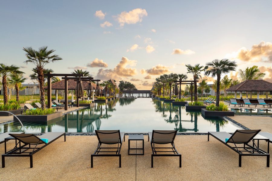 An outdoor pool with lounge chairs and palm trees at Anantara Desaru Coast Resort & Villas. 