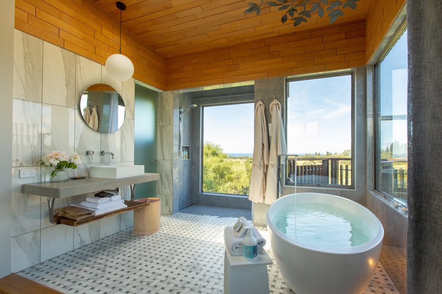 The bathroom of a Tree House at Hapuku Lodge, Kaikoura, with a view of the trees outside. 