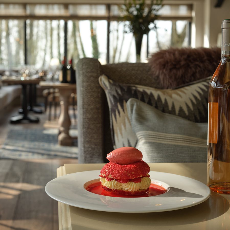 A red-fruit dessert and a bottle of wine on the coffee table in a treehouse at The Fish Hotel in the Cotswolds.