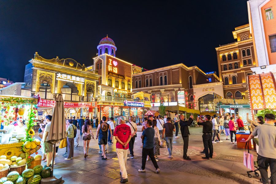 People walking around the Xinjiang International Grand Bazaar at night.
