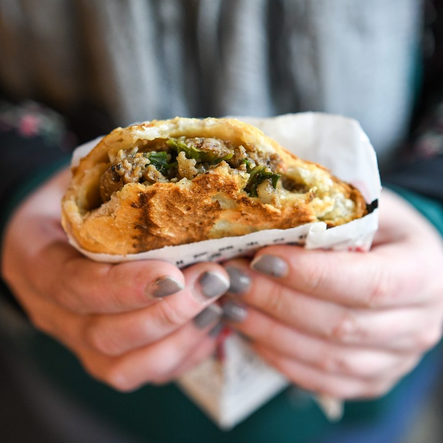 A person with grey painted nails holds onto a pepper pie, a popular food available at Raohe Night Market from the Fuzhou Ancestor Pepper Pie stall. 
