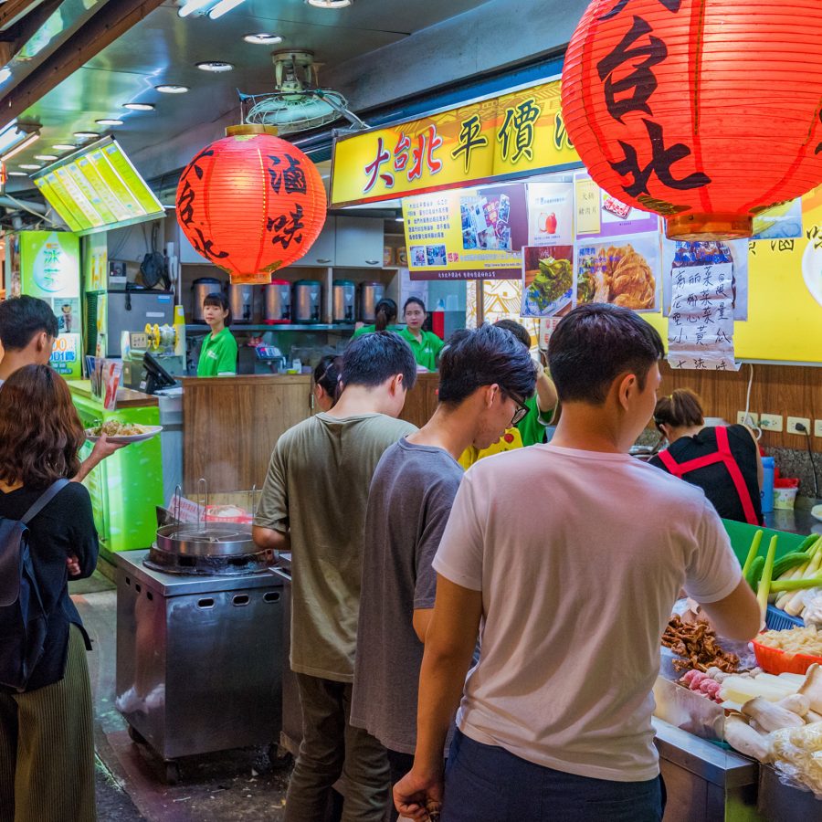 Visitors line up in front of a stall selling street food at Shida Night Market, which is known for fried chicken and herbal teas alongside other foods. 