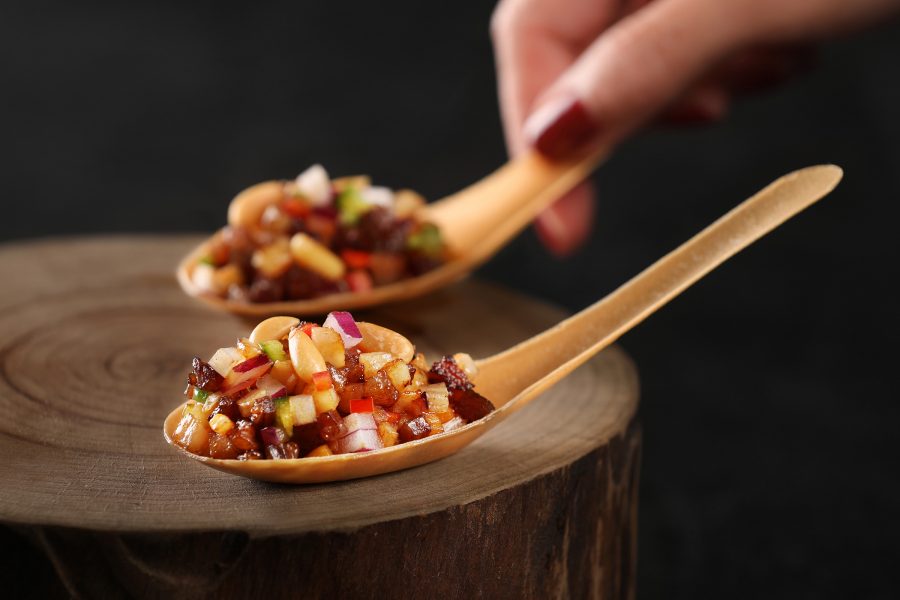 A closeup of a hand holding a spoon filled with diced vegetables and halal beef, served at Chinesology contemporary Chinese restaurant in IFC, Hong Kong.