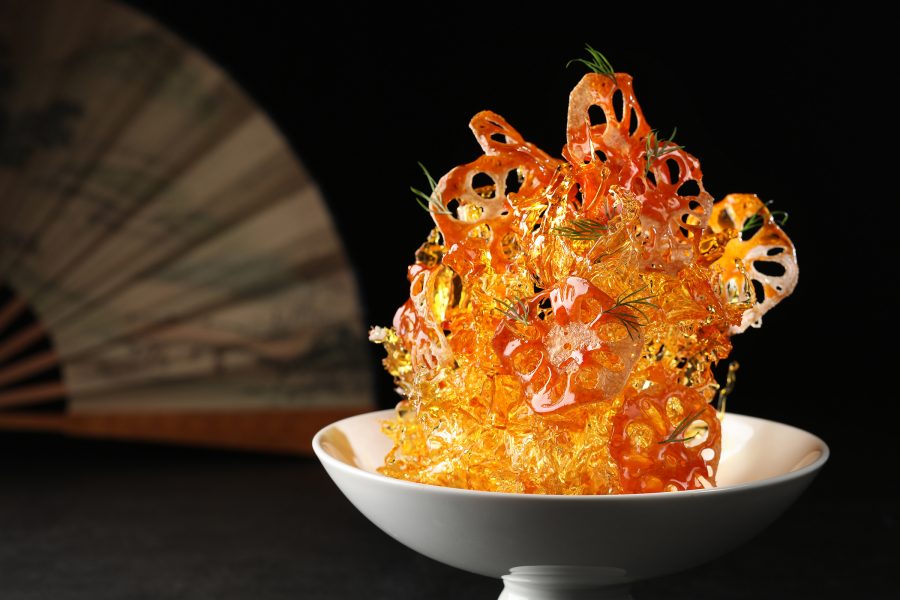  A golden tower of candied lotus root on a white plate, served at Chinesology contemporary Chinese restaurant in IFC, Hong Kong.
