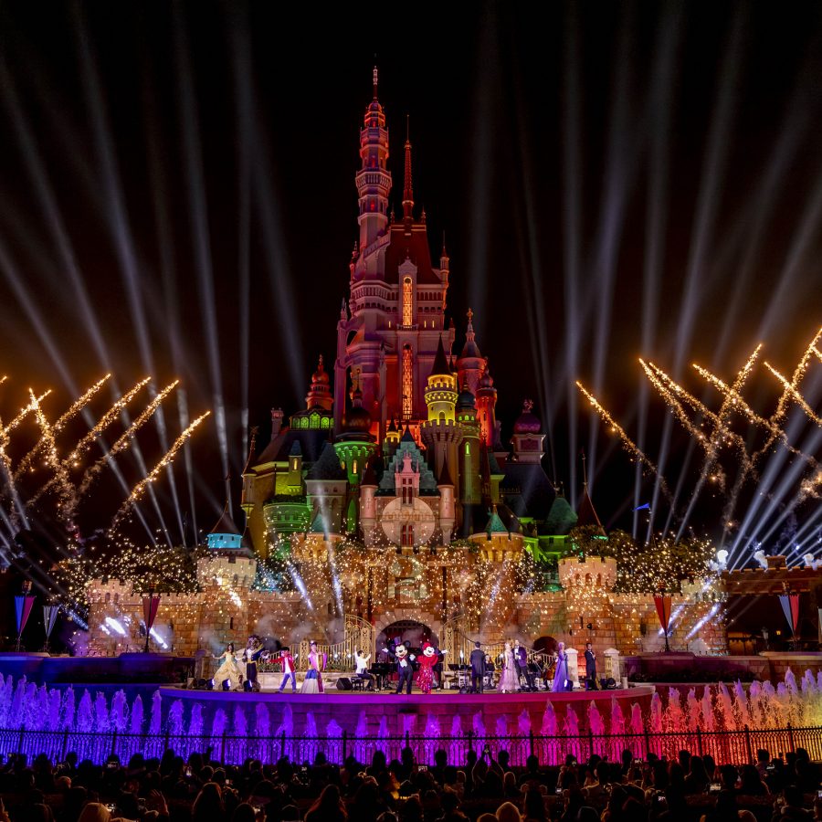 A view of the Momentous Nighttime Spectacular fireworks show at the Castle of Magical Dreams with a crowd watching at Hong Kong Disneyland.